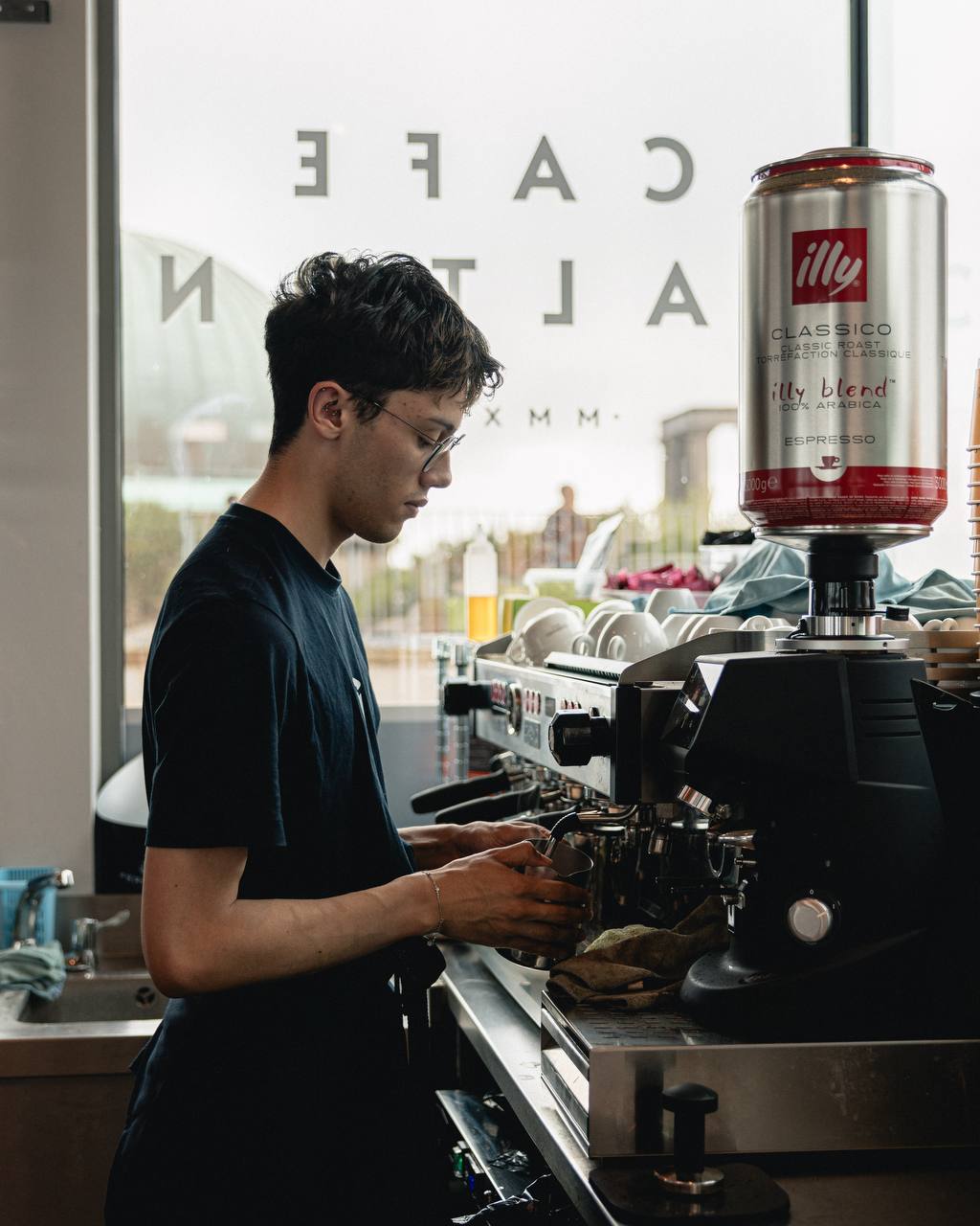 Focused in the morning light, a barista crafts a morning brew at Café Calton, capturing a cinematic moment of urban craft. Focused in the morning light, a barista crafts a morning brew at Cafe Calton, capturing a cinematic moment of urban craft.