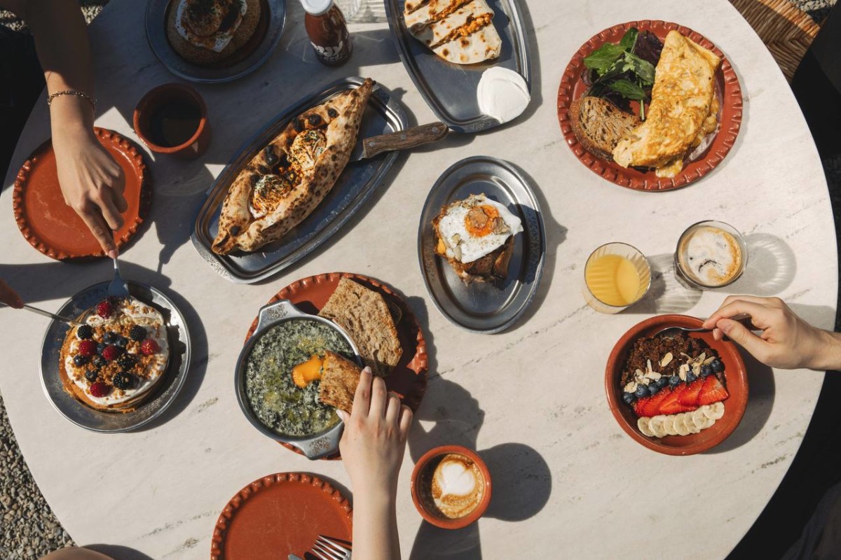 Overhead view of Mediterranean and Greek breakfast including flatbreads, dips, stuffed pastries and savoury pies on a marble table at ERGON House