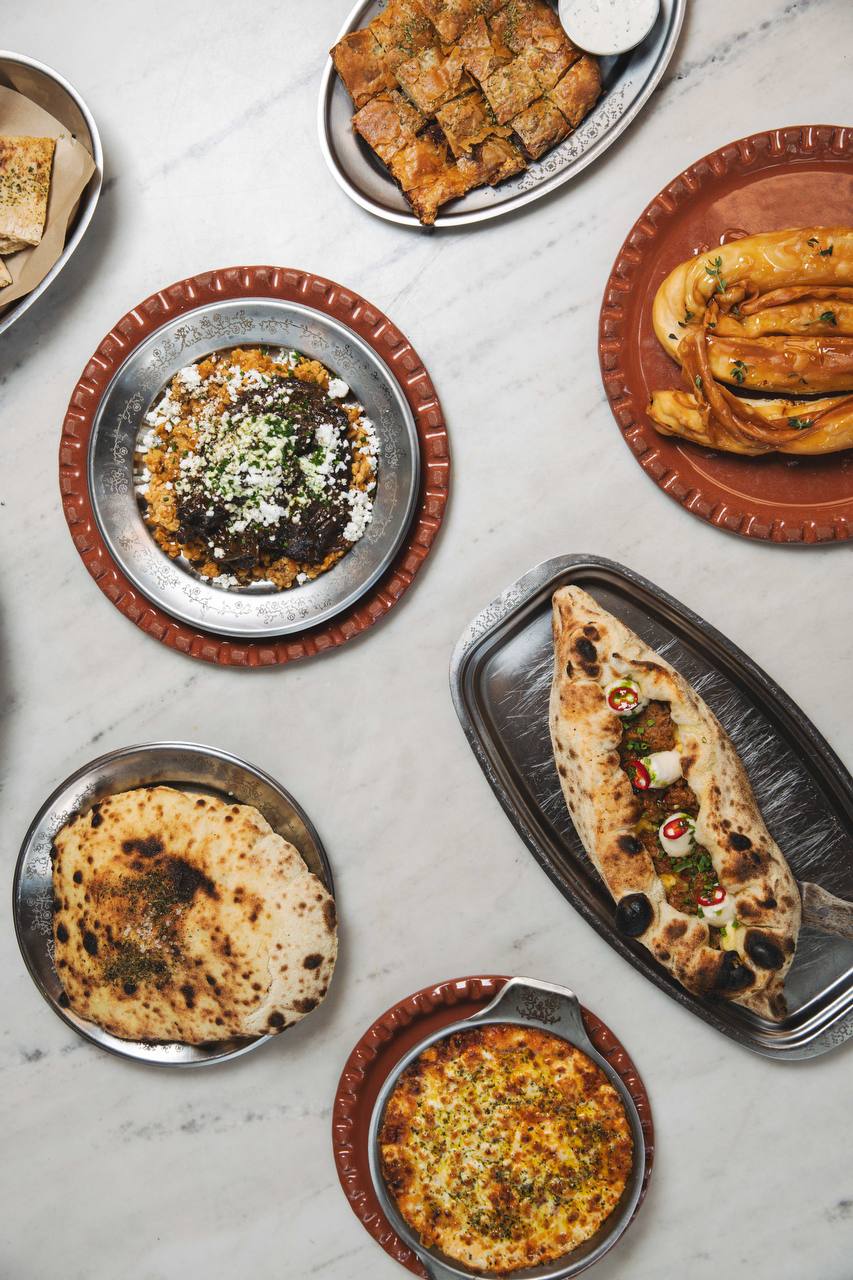 Freshly baked flatbreads and oven-baked Greek dishes served on a marble table at ERGON House Athens.