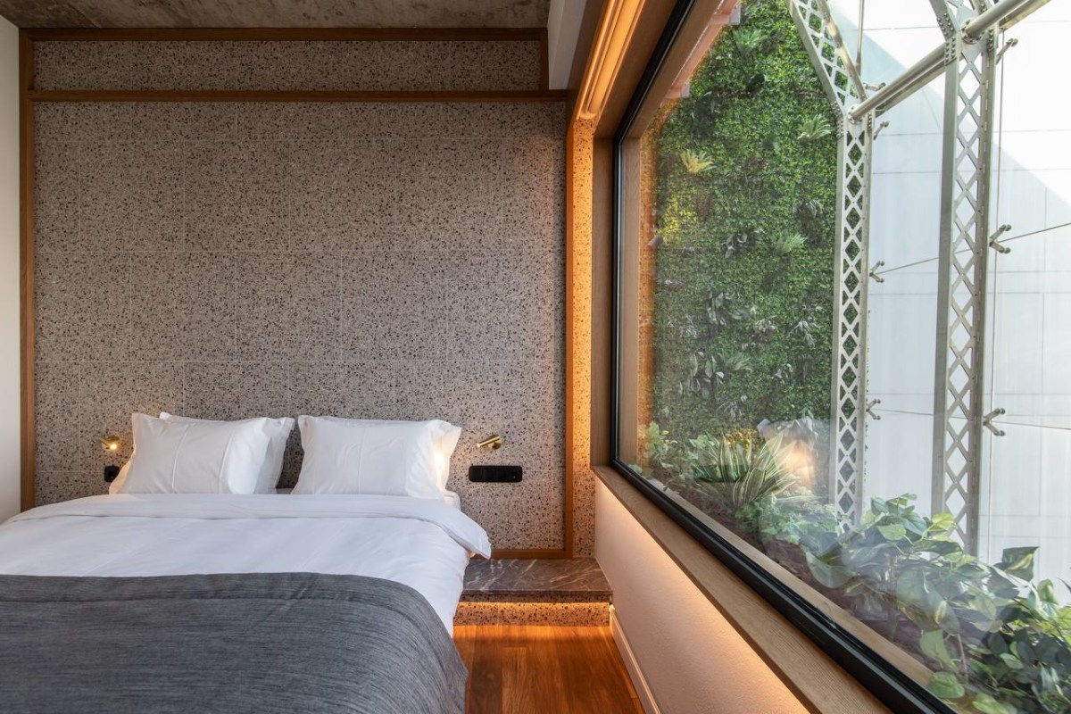Minimalist studio room at ERGON House Athens with warm wooden floors, raised platform bed and exposed concrete ceiling