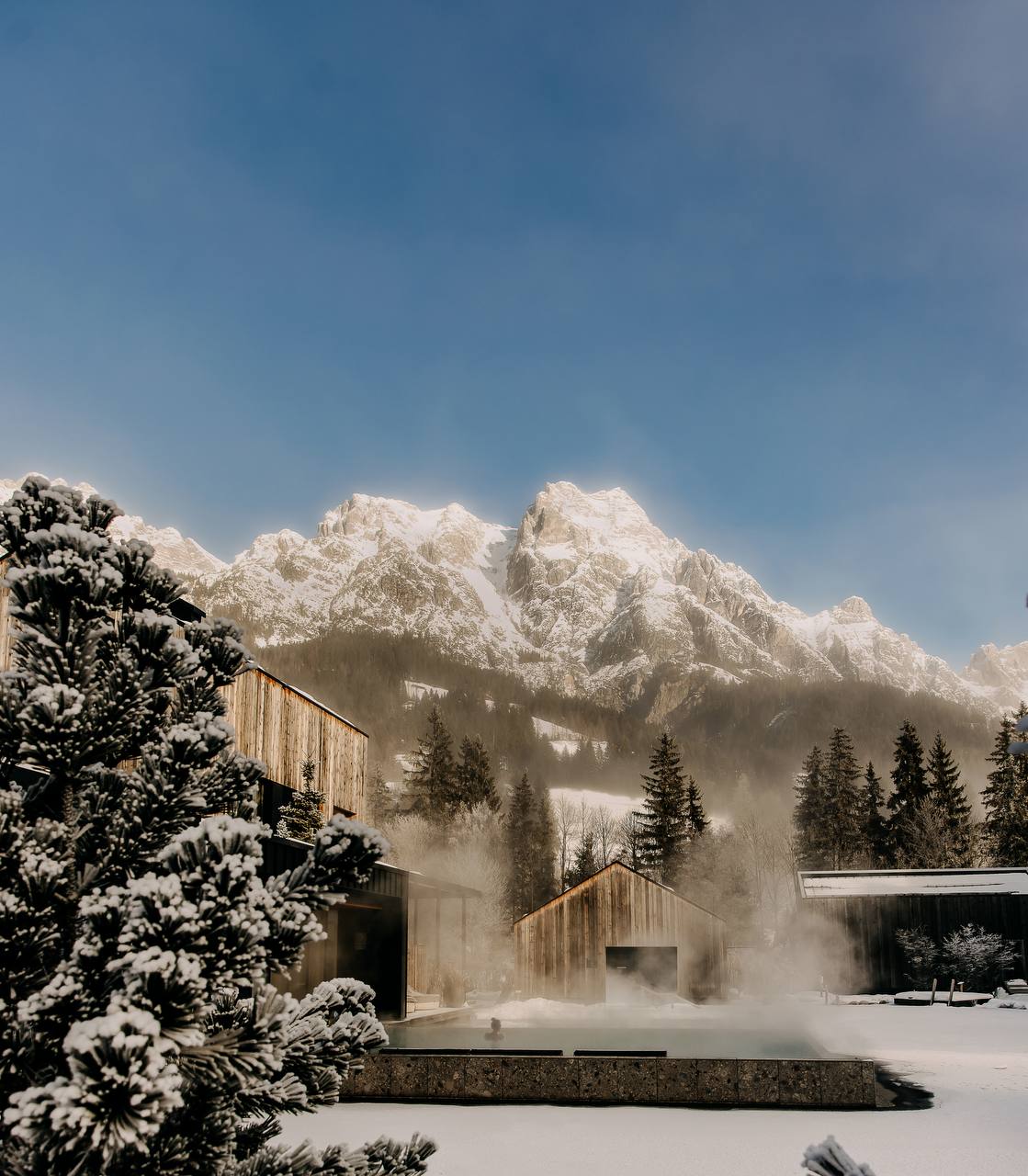 Outdoor thermal pool steaming against snow-covered mountains