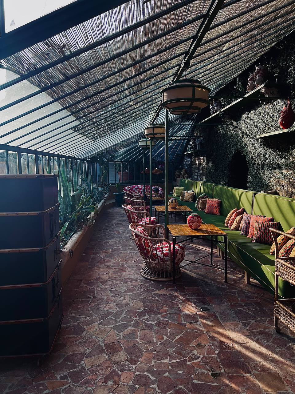 Conservatory lounge with green banquettes and wicker chairs at Passalacqua