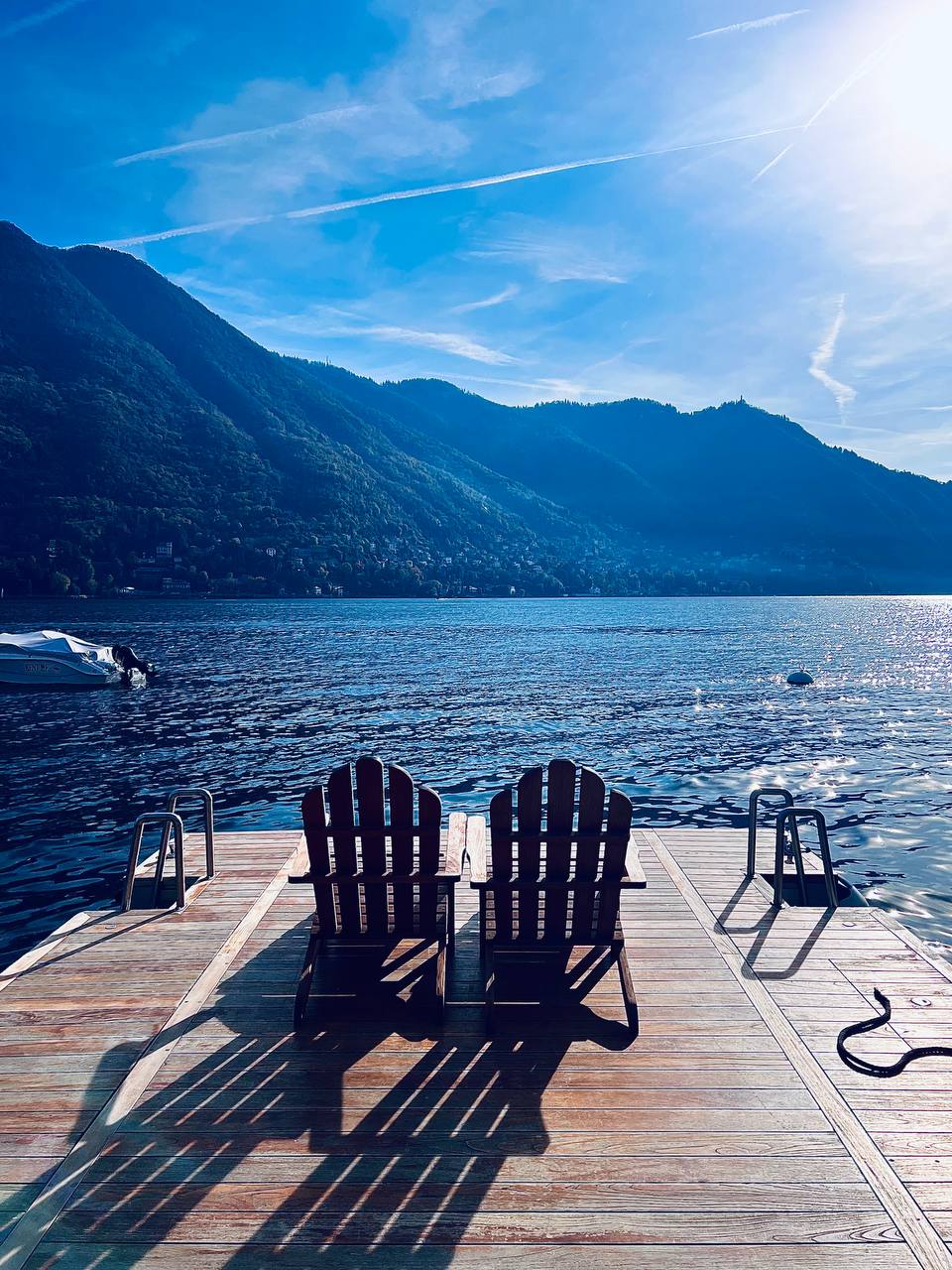 Two Adirondack chairs on the private dock at Passalacqua overlooking Lake Como