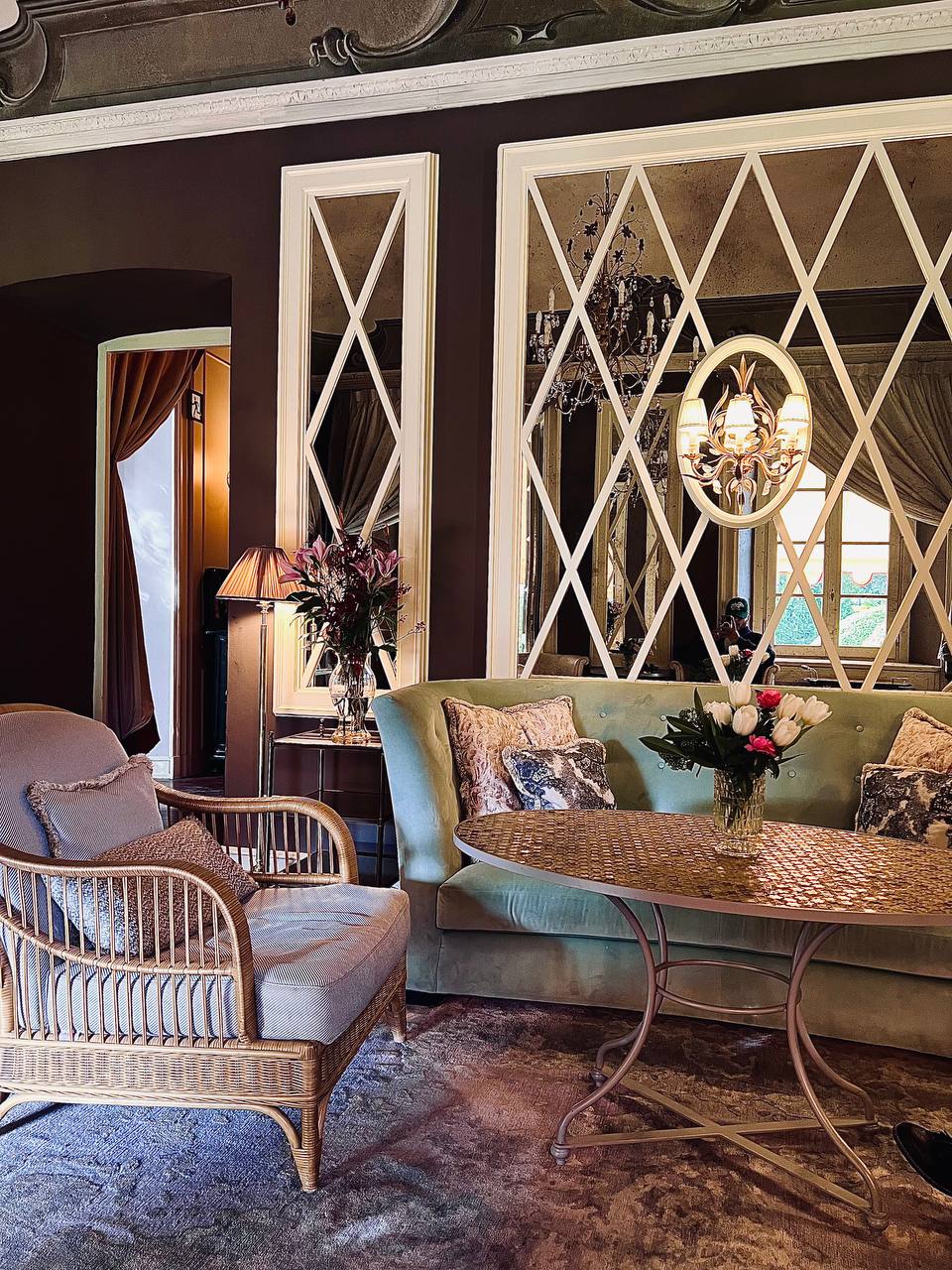Sage green velvet sofa and ornate mirrors in Passalacqua sitting room