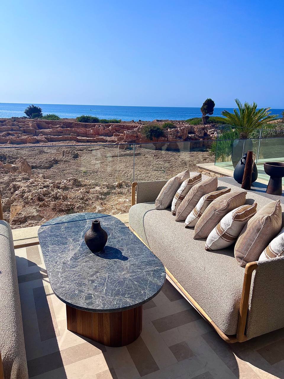 Outdoor terrace with seating overlooking archaeological ruins and the sea at Amoh Rhodes
