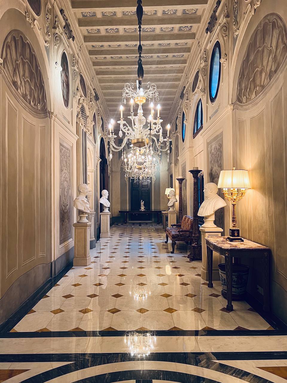 Grand hallway with marble busts and crystal chandeliers