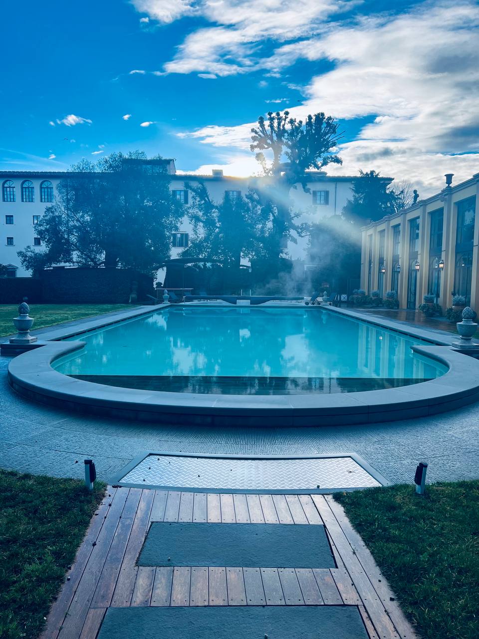 Outdoor pool surrounded by manicured parkland grounds