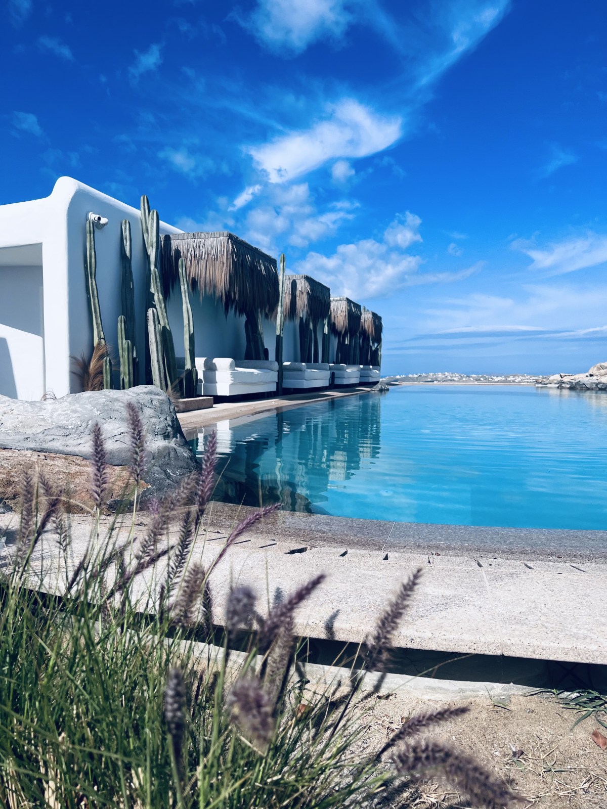 Infinity pool with white thatched cabanas at Panoptis Escape Mykonos