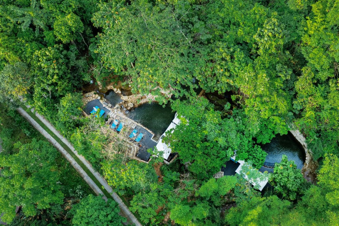 Aerial view of natural spring-fed lagoons surrounded by tropical forest at Avana Retreat