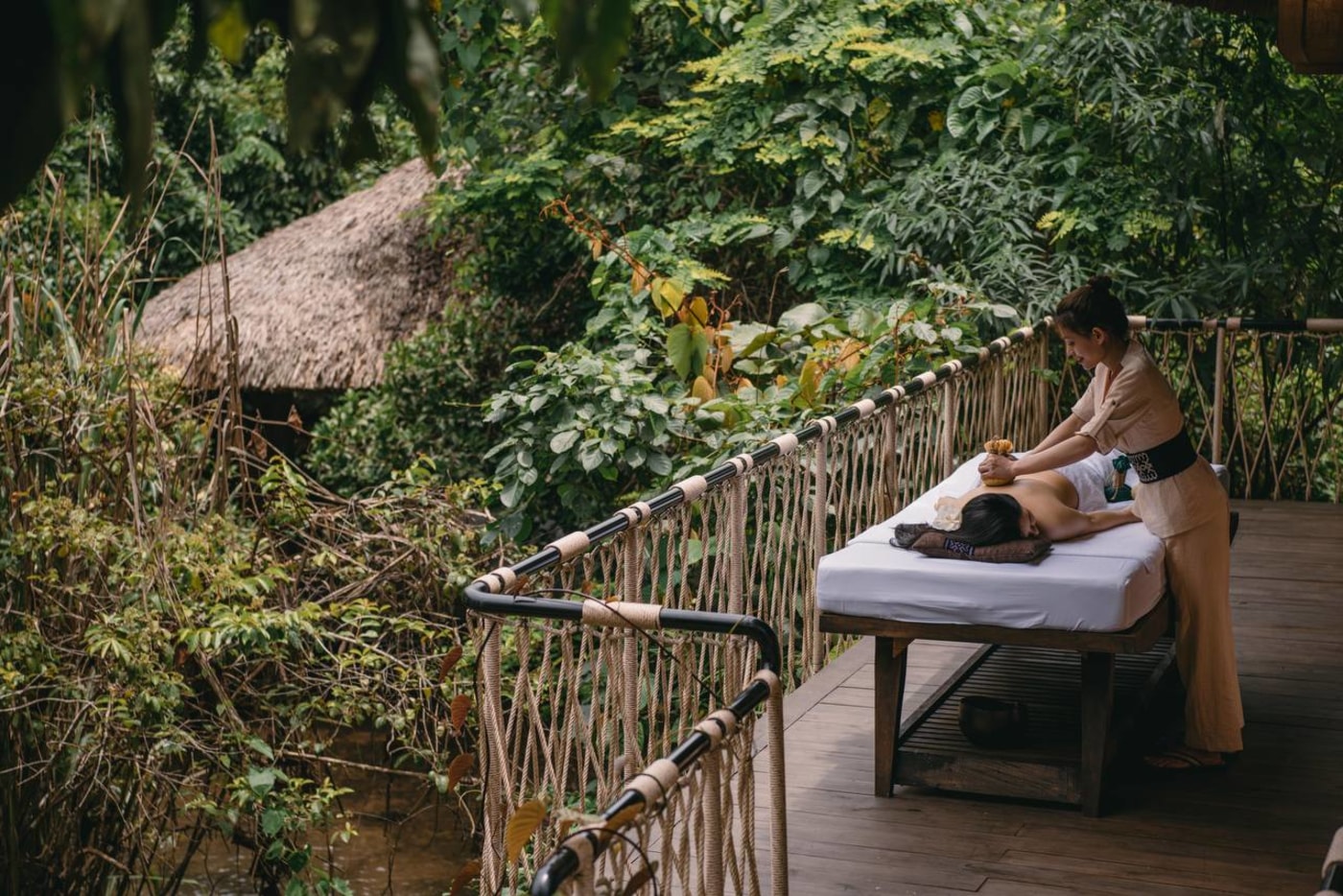 Outdoor massage on elevated wooden deck surrounded by jungle at Avana Retreat