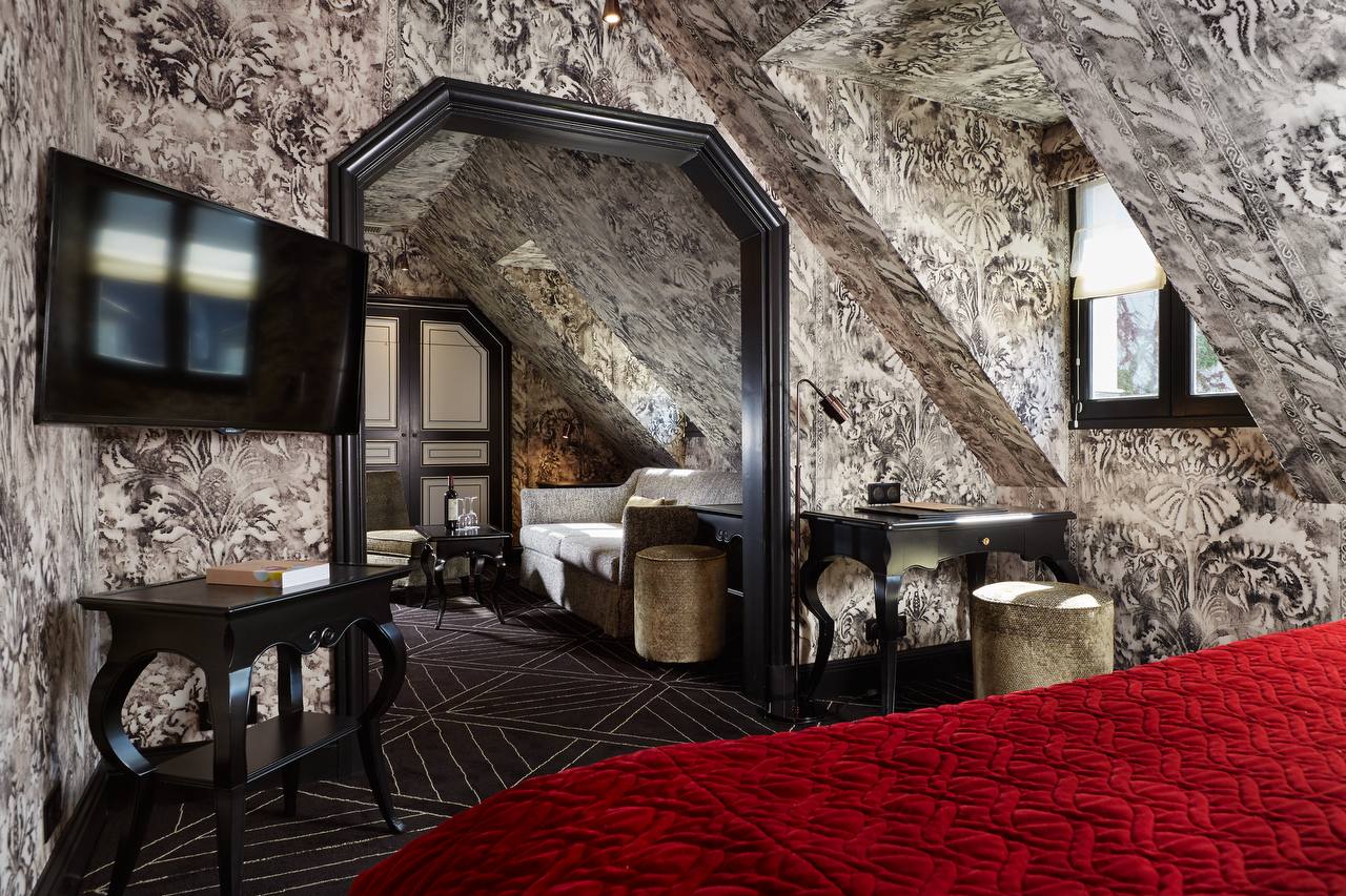 Suite with scenic toile wallpaper and red velvet at Pavillon de la Reine