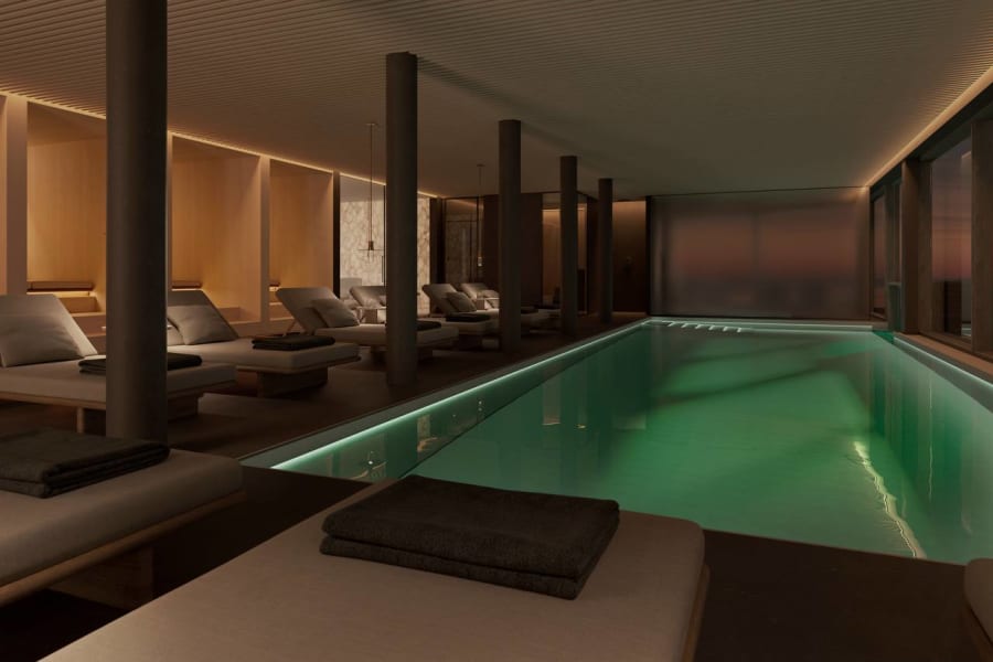Indoor spa pool with illuminated turquoise water and stone columns
