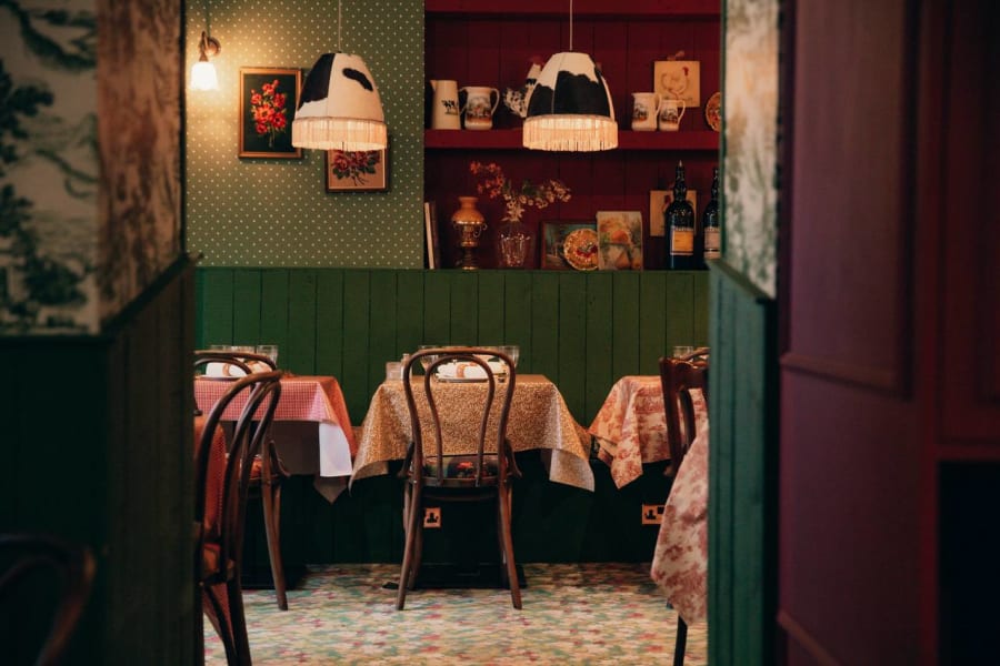 Cosy dining nook with green wainscoting and cow-print pendant lamps at Josette