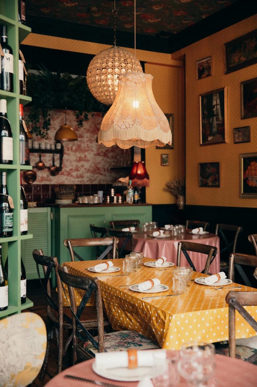 Restaurant interior with warm pendant lighting and yellow tablecloths at Paulette