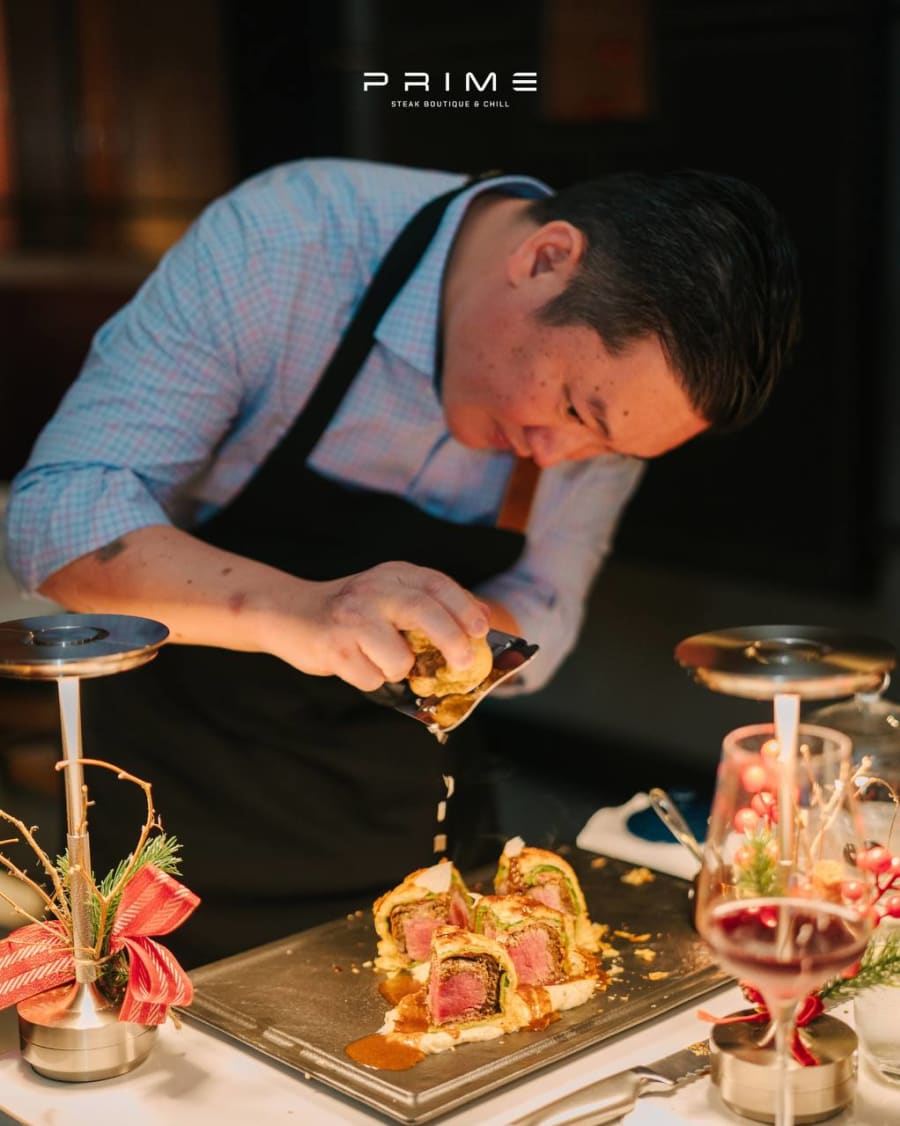 Chef Khải Vũ finishing Beef Wellington tableside at PRIME Steak Boutique, drizzling jus over the pastry