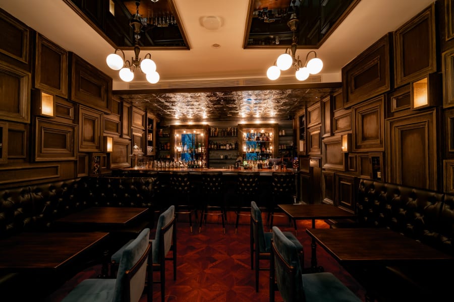 Globe chandeliers cast warm light over tufted leather banquettes on the third floor at Speak Low
