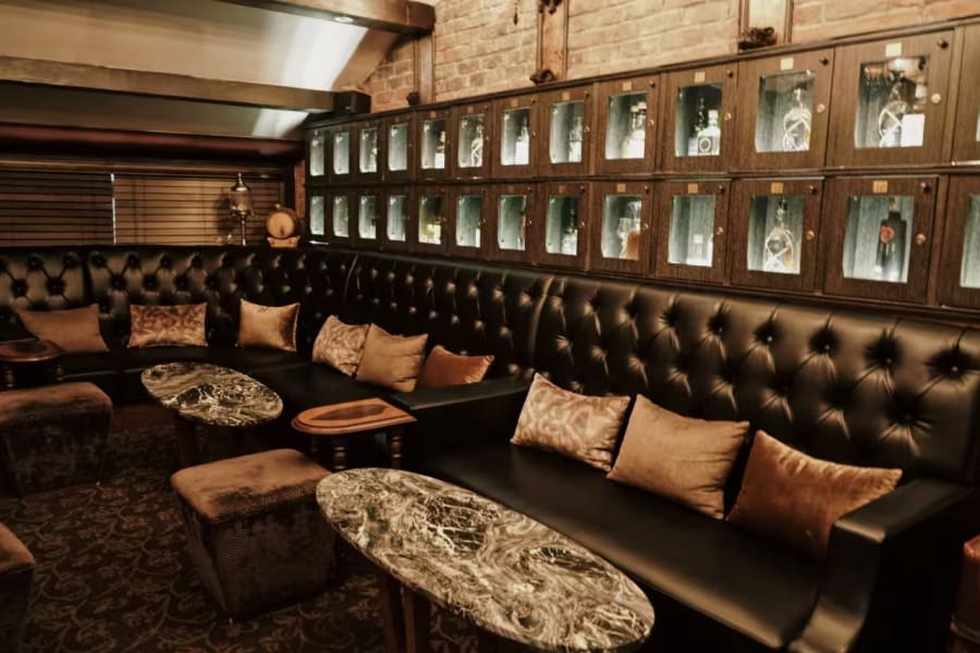 Tufted leather banquette with marble tables and bottle lockers at Speak Low fourth floor