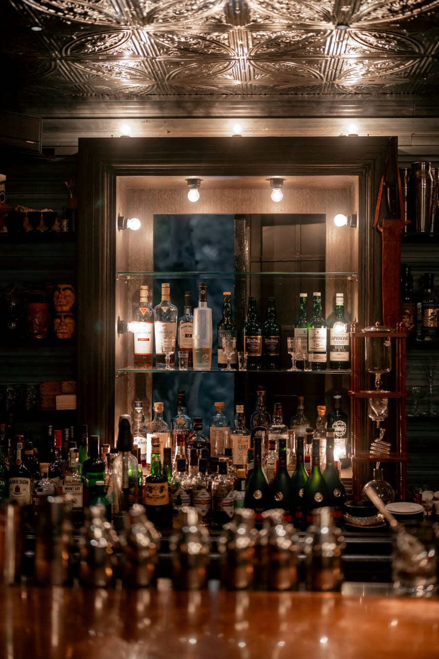 Mirrored backbar with illuminated bottles at Speak Low
