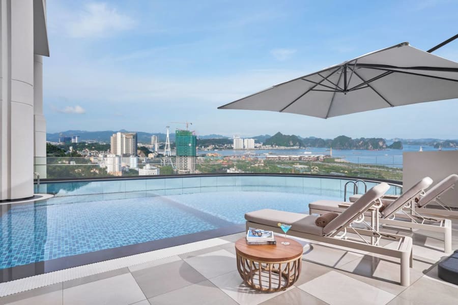 Rooftop infinity pool with lounge chairs and panoramic bay views