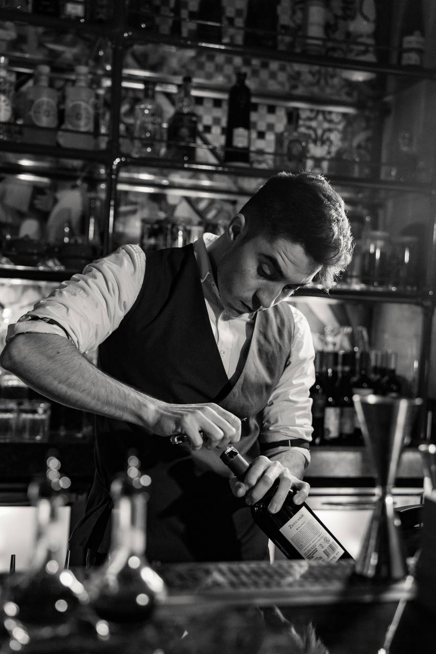 Bartender opens a bottle behind the stocked bar at Felicità
