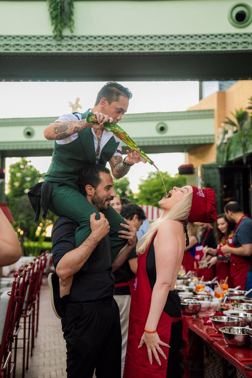 Bartender pours drink from shoulders during a lively culinary event at Felicità