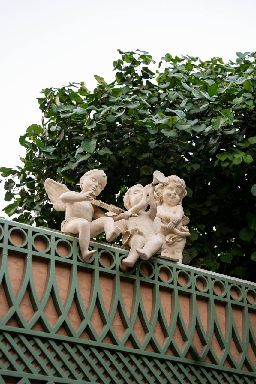 Cherub musicians perched on ornate green lattice wall at Felicità