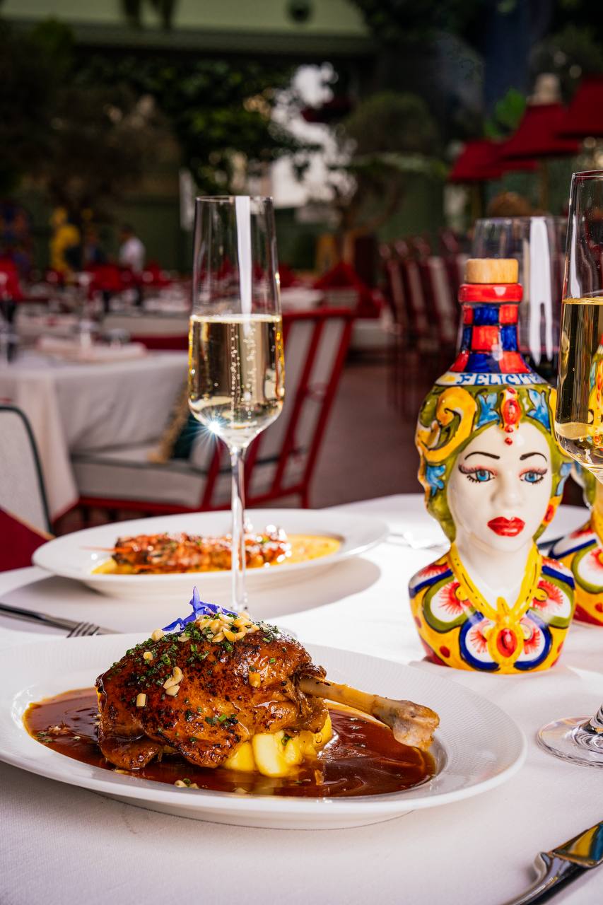 Table setting with duck dish, sparkling wine and ceramic head vessel at Felicità
