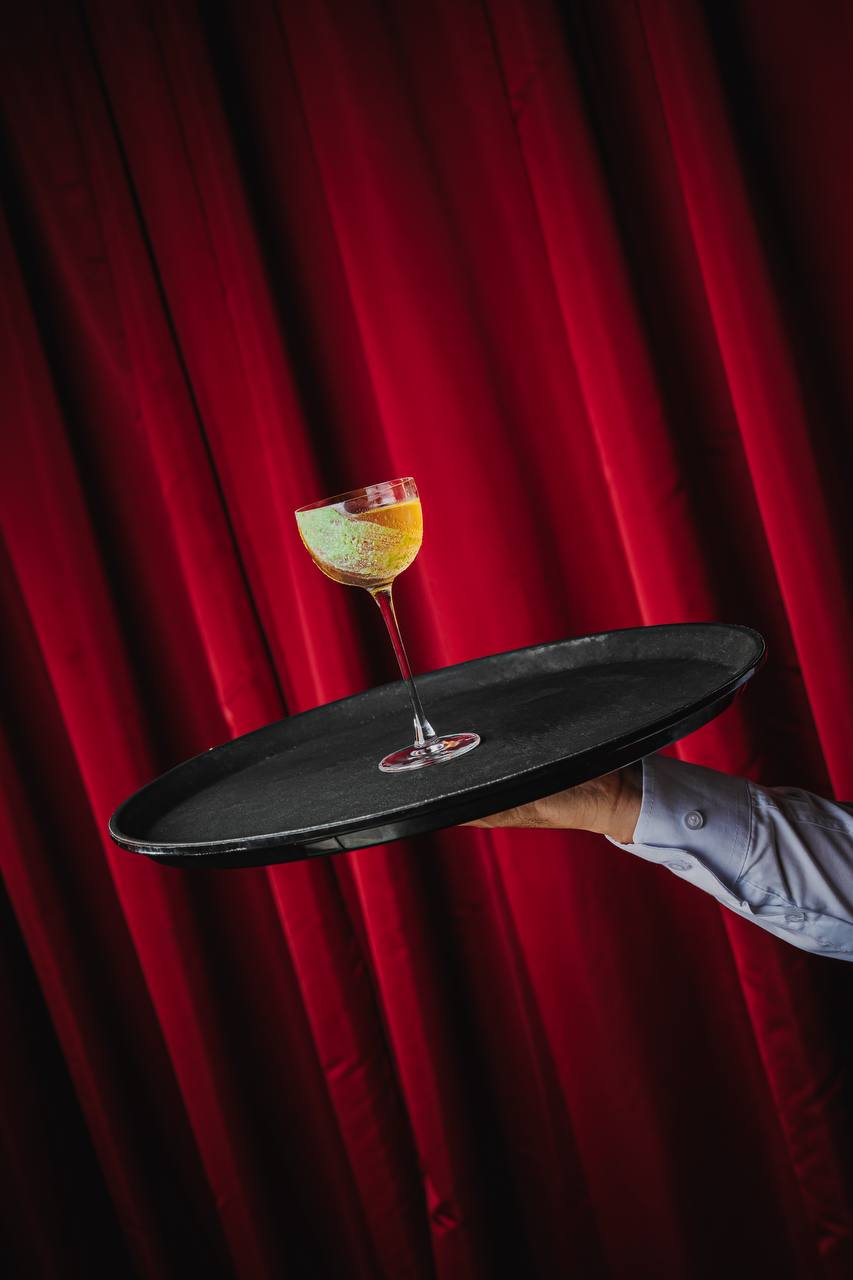Golden cocktail against red velvet curtains at Felicità Dubai