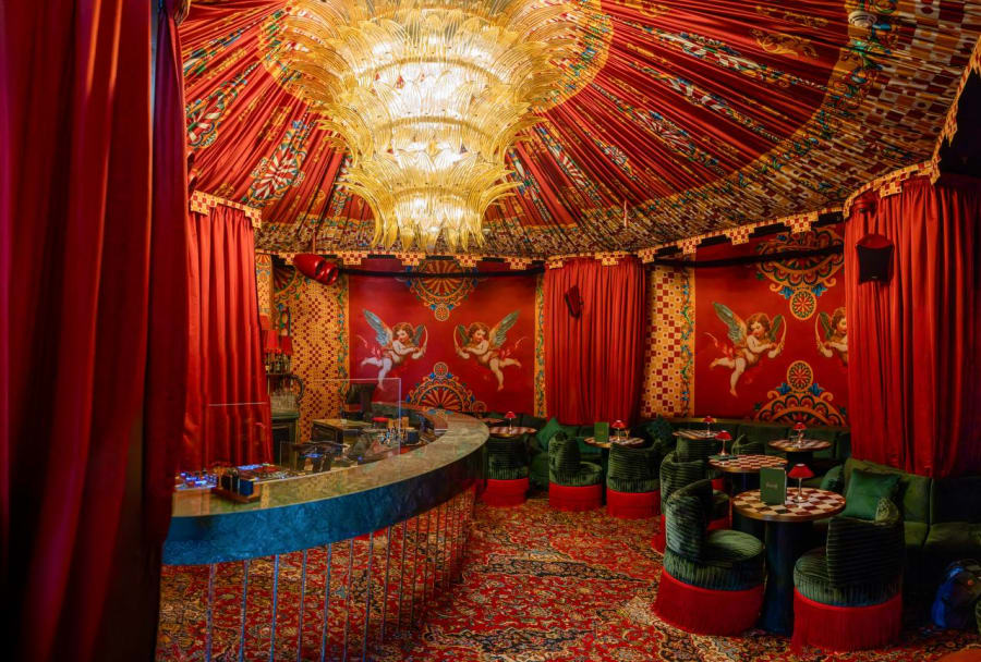 Opulent red bar with cherub murals, crystal chandelier and green velvet seating at Felicità