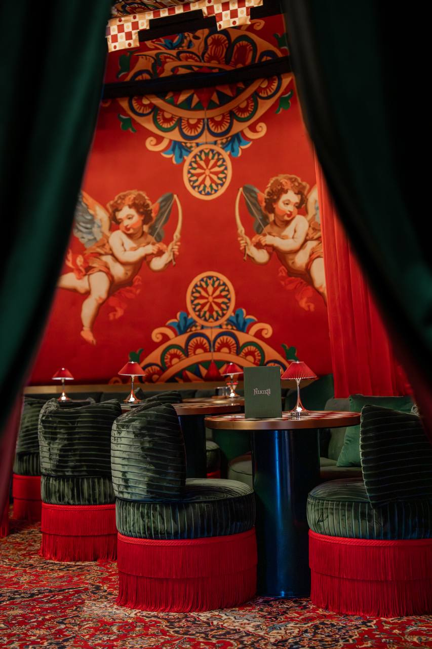 Red lounge with cherub murals, crimson lamps and velvet seating at Felicità Dubai