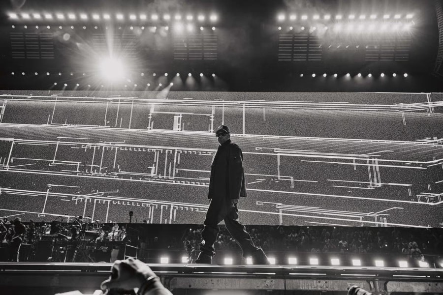 Jay-Z performing on stage at Tottenham Hotspur Stadium in dramatic black and white, silhouetted against a massive LED screen