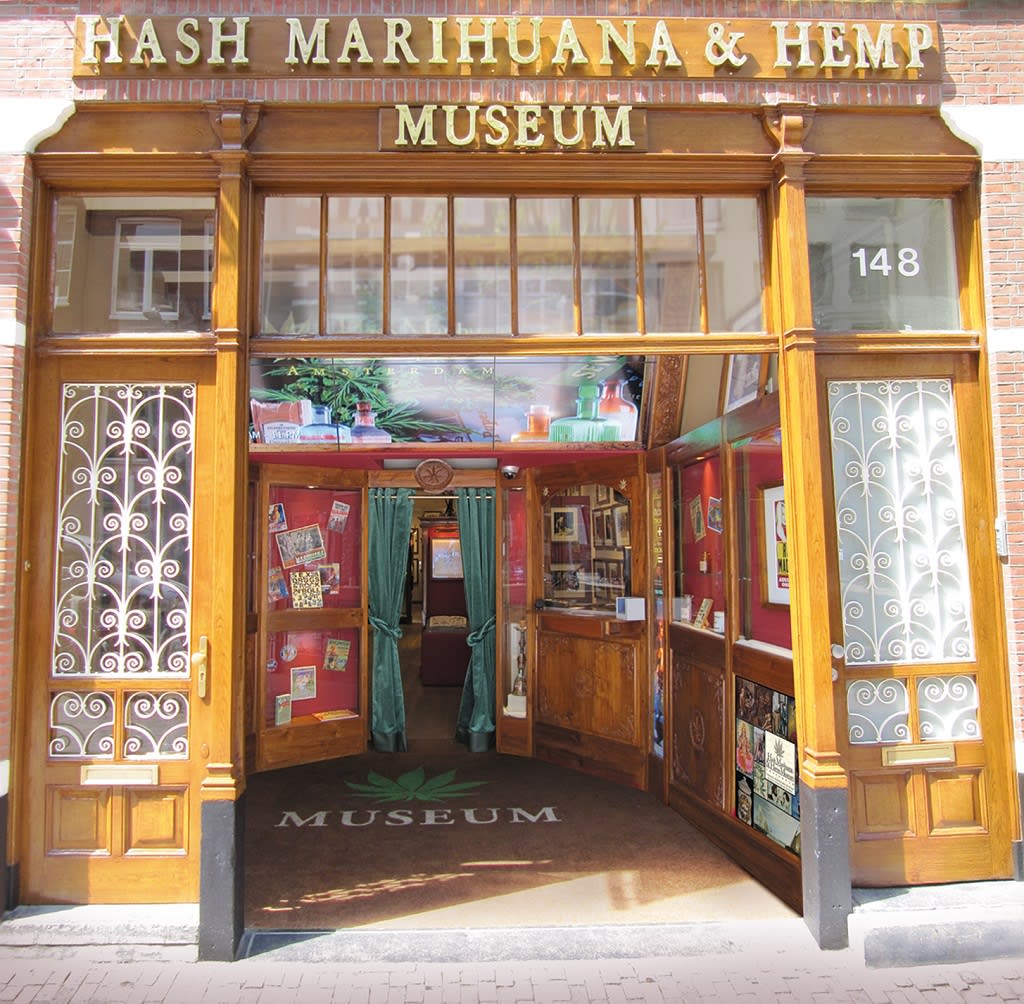 Entrance to the Hash Marihuana & Hemp Museum with wooden doors, green curtains, and exhibits.