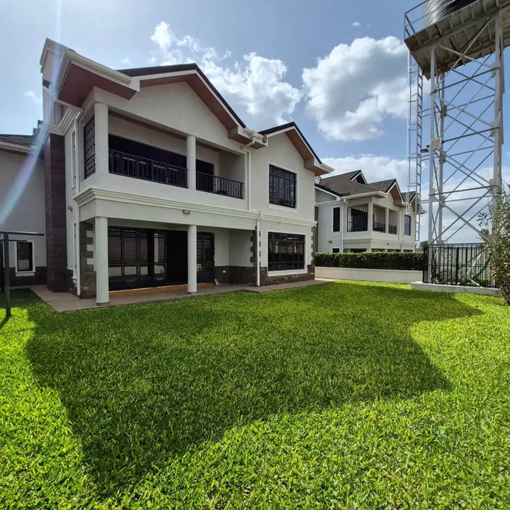 Freshly mown striped lawn with a mower at the edge beside a green hedge