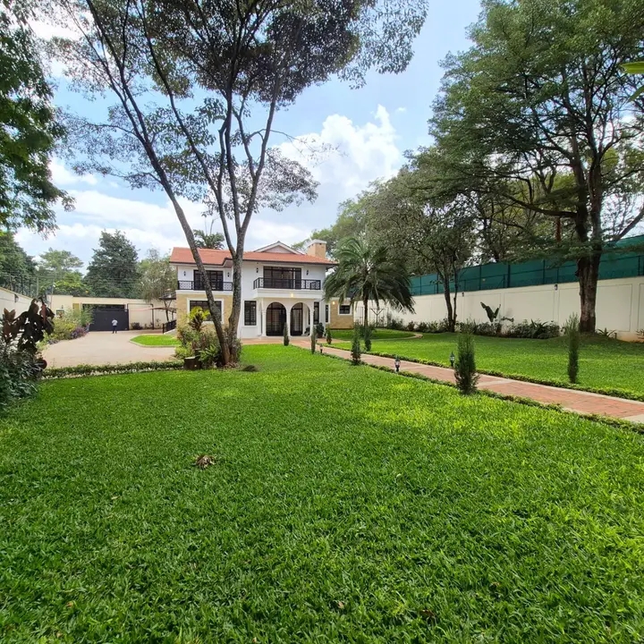 Modern residential front compound with trimmed lawn, low hedges and paved driveway