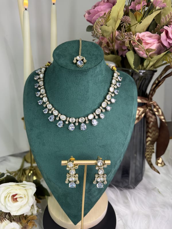Close-up of the American Diamond Kundan necklace and earrings set against a decorative green background.