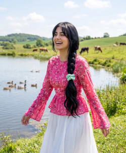 Happy Woman in Pink Floral Blouse Walking by Scenic Countryside Lake