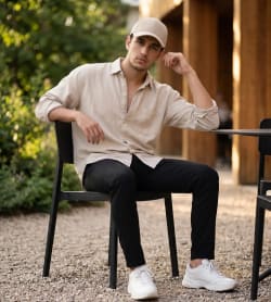 Casual Young Man in Beige Shirt Seated at Outdoor Cafe