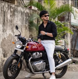 Stylish Man Sitting on Red Royal Enfield Motorcycle in Urban Setting