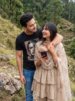 Playful Young Couple Embracing on a Grassy Hillside Outdoors