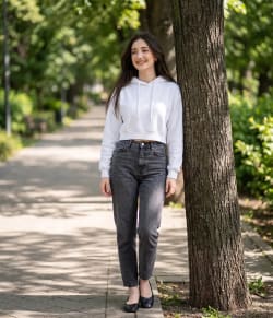 Outdoor Lifestyle Fashion Portrait of Woman Leaning Against Park Tree