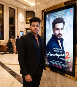 Young Man in Black Suit Standing Beside Movie Poster in Marble Foyer
