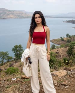 Woman in Red Crop Top Standing on Scenic Hillside Overlooking Lake