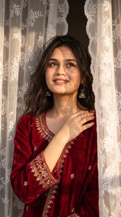 Sunlit Portrait of Woman in Crimson Velvet Behind Lace Curtains