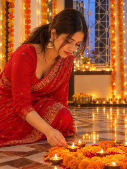 Young Woman in Red Saree Lighting Diyas for Diwali Celebration