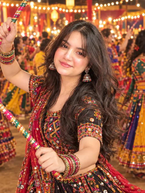 Young Woman in Black Mirror Work Chaniya Choli Holding Dandiya Sticks at Garba Night