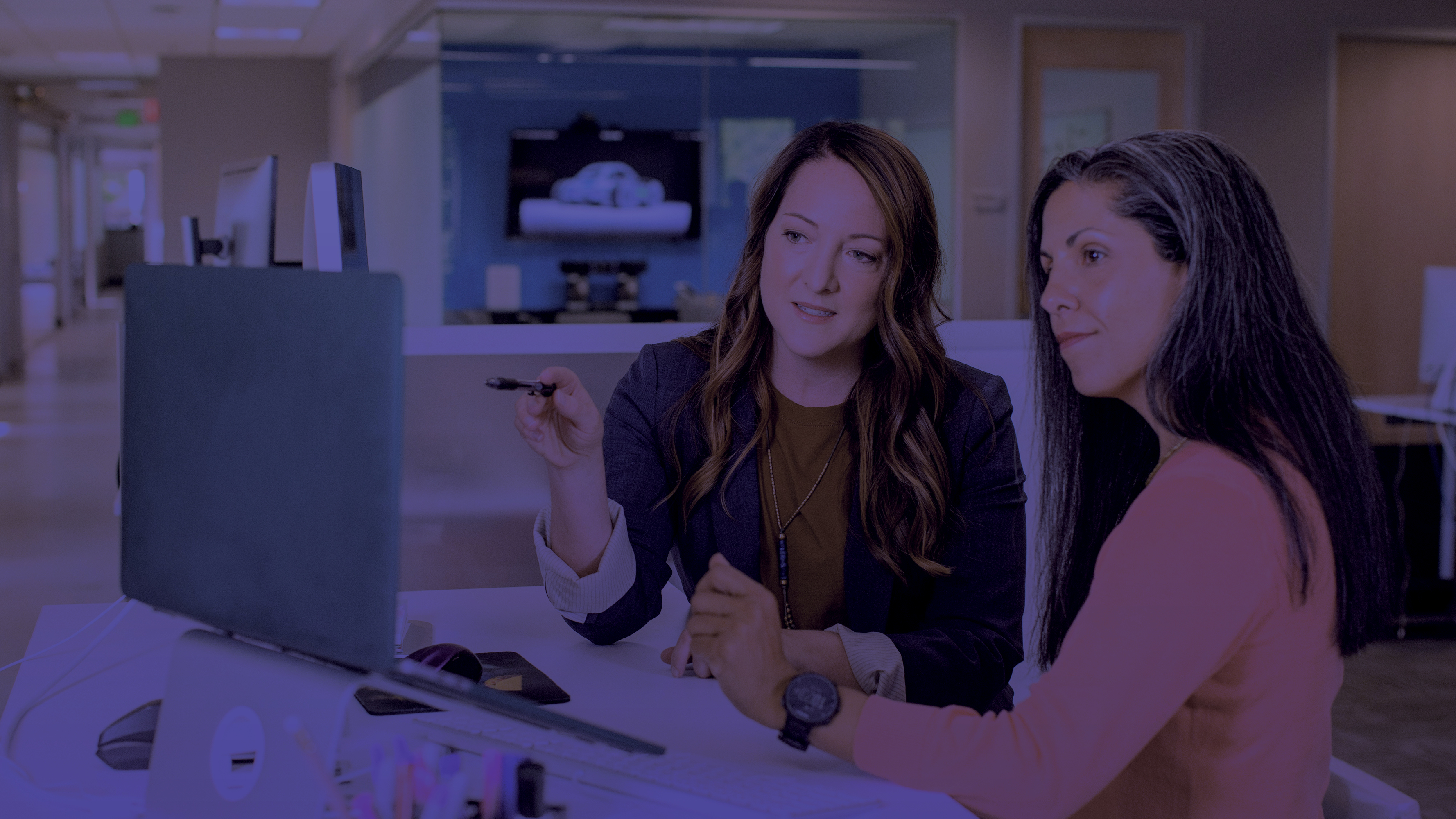 Two women sitting at a desk looking at a computer