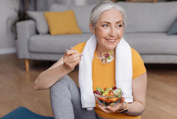 a woman eating a salad on a yoga mat