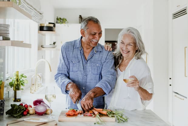 a couple cutting food in the kitchen