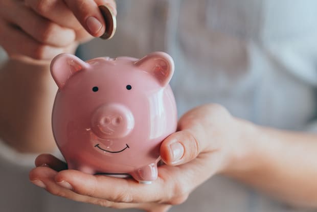 a person putting a coin into a piggy bank