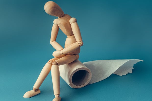 a wooden figurine sitting on a roll of toilet paper